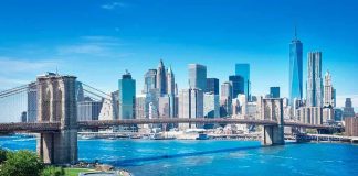 Brooklyn Bridge spanning blue river with modern city skyline