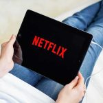 Person holding a tablet with streaming app on screen