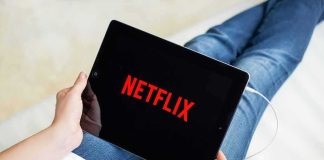 Person holding a tablet with streaming app on screen