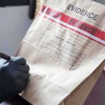 Prosecutors Detail Backpack Evidence Gloved hands labeling a sealed evidence bag