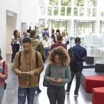 Stanford Breaks Its Own AI Policy Students walking through a bright campus lobby using mobile devices