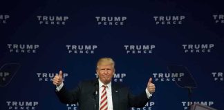 man at podium giving two thumbs up
