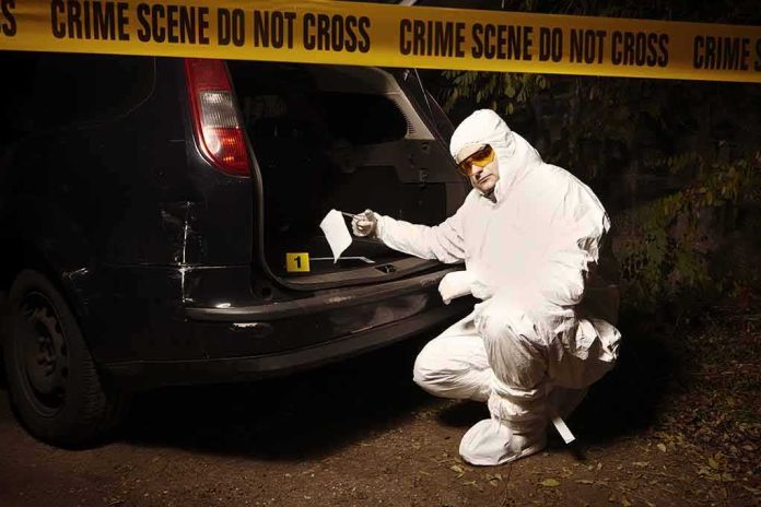 shutterstock_515360554 forensic investigator at car trunk behind crime scene tape