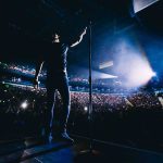 Promoter Power Play: Sheeran Says It Wasn’t His Decision Singer on stage facing a large concert crowd