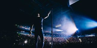 Singer on stage facing a large concert crowd