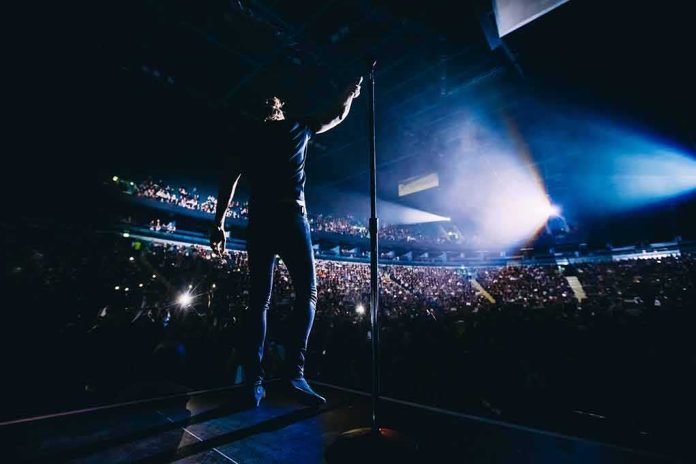 Singer on stage facing a large concert crowd