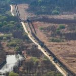 Trade Freeze Slams West Bank Goods Border fence and patrol road cutting through dry landscape with sparse trees