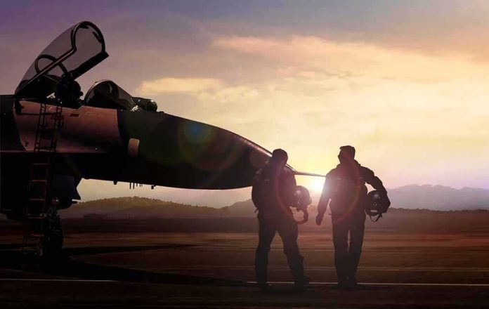 shutterstock_680854186 Two pilots walking beside a fighter jet at sunset