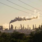 Energy “Truce” Fails to Stop Strikes Industrial refinery with smokestack emitting plume at sunset