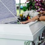 Guatemala Investigates Teen’s Mistaken Death hands resting on a white casket with flowers nearby
