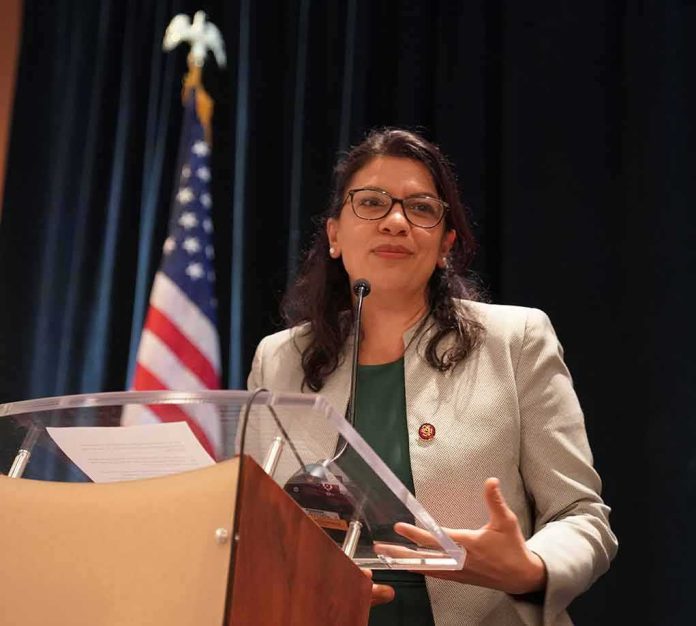 shutterstock_1281099373 Rashida Tlaib speaking at a podium with a U.S. flag in the background