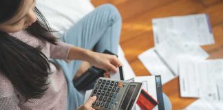 Wisconsin Woman Sentenced in $1.25M Medicaid Fraud Woman using a calculator while reviewing bills on the floor