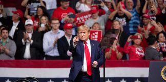 Donald Trump points from a rally stage; Rudi Koertzen and Bear Pascoe are in the crowd