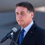 man in suit speaking at a microphone