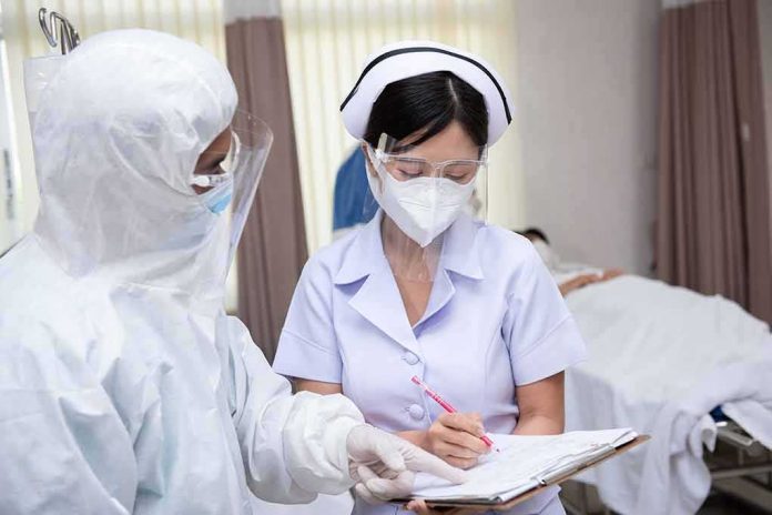 shutterstock_1823374517 nurse in PPE writing on a clipboard with colleague