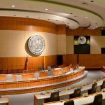 Wartime Tech Disruptions Raise Alarm Interior view of a government chamber with wooden paneling and seating