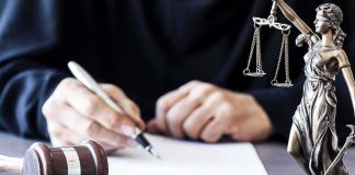 Legal Battle Sparks Controversy Judge writing at desk with gavel and Lady Justice statue
