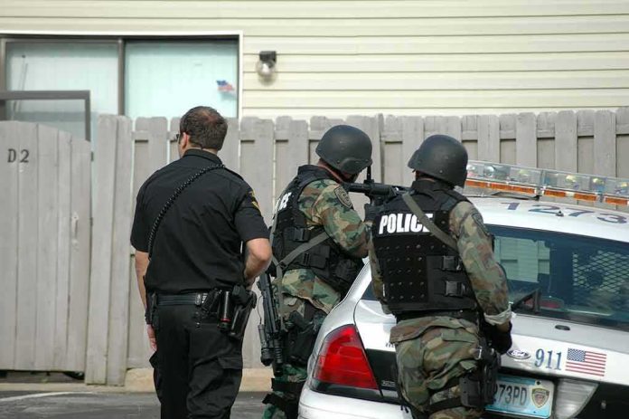shutterstock_728435 police officers in tactical gear beside patrol car