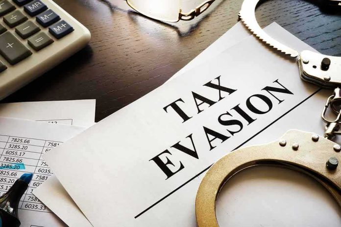 shutterstock_733660624 Handcuffs and calculator on tax evasion document